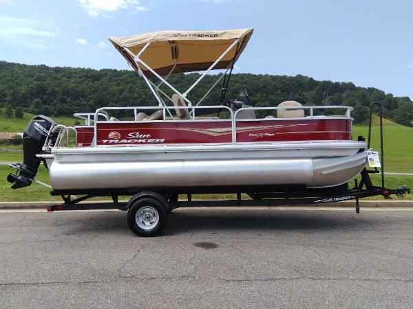 Slide: The Image of 2024 Sun Tracker Bass Buggy 18 DLX pontoon boat on trailer, red with tan canopy. - 0