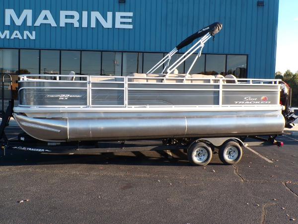 Slide: The Image of 2024 Sun Tracker FISHIN' BARGE® 22 DLX pontoon boat on trailer outside marine dealership. - 3