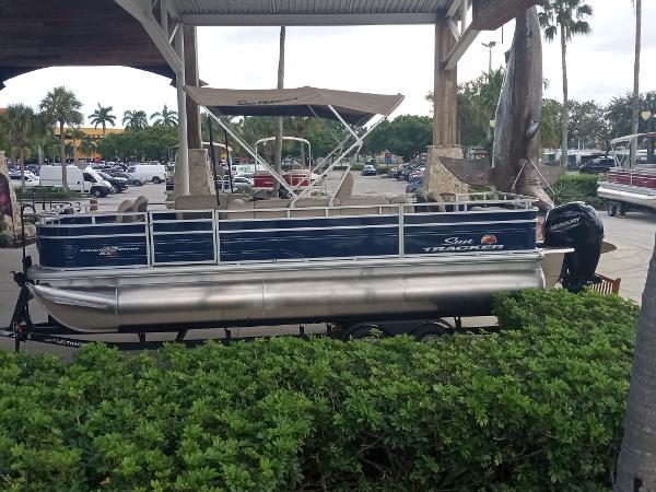 Slide: The Image of 2024 Sun Tracker Fishin' Barge 22 XP3 pontoon boat on display outdoors. - 1