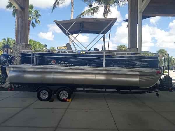 Slide: The Image of 2024 Sun Tracker Fishin' Barge 22 XP3 pontoon boat on a trailer under a canopy. - 4