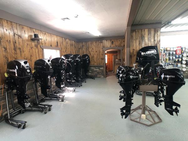 Slide: The Image of Showroom with multiple Tohatsu and Suzuki outboard motors on display. - 12