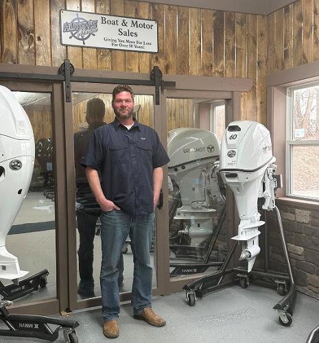 Slide: The Image of Man standing in boat and motor sales showroom with outboard motors. - 14