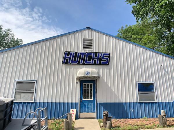 Slide: The Image of Hutch's storefront with blue and white exterior, trees, and clear sky. - 16
