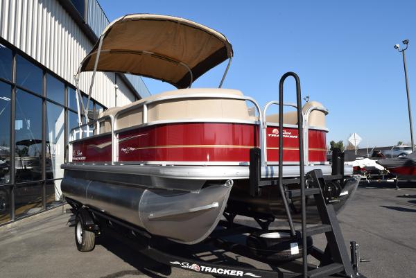 Slide: The Image of 2024 Sun Tracker Party Barge 18 DLX pontoon boat on trailer, red and beige color scheme. - 1