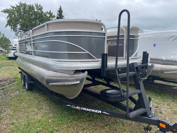 Slide: The Image of 2023 Sun Tracker Party Barge 20 DLX pontoon boat on trailer, parked outdoors. - 1