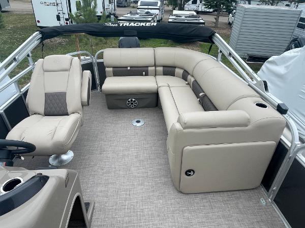 Slide: The Image of 2023 Sun Tracker Party Barge 20 DLX interior with beige seating and helm chair. - 4