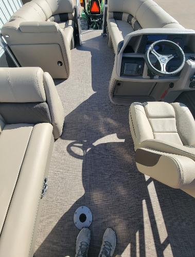 Slide: The Image of 2024 Sun Tracker Party Barge 20 DLX interior with beige seating and steering console. - 2