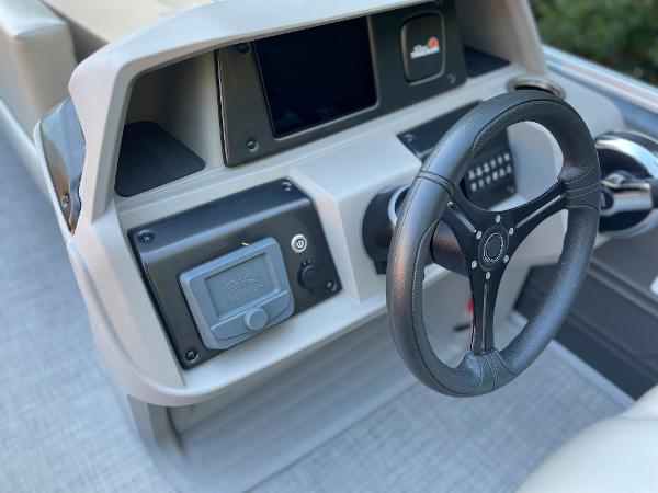 Slide: The Image of 2024 Sun Tracker Party Barge 20 DLX steering console with modern controls and black steering wheel. - 5