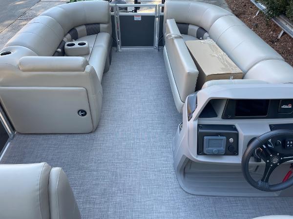 Slide: The Image of 2024 Sun Tracker Party Barge 20 DLX interior with beige seating and modern helm. - 6