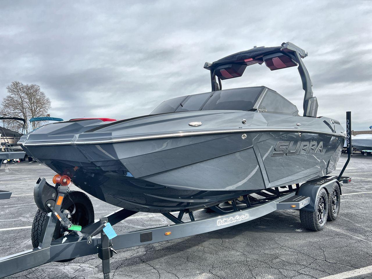 Slide: The Image of 2025 Supra SA boat on trailer, sleek design, parked outdoors under cloudy sky. - 1