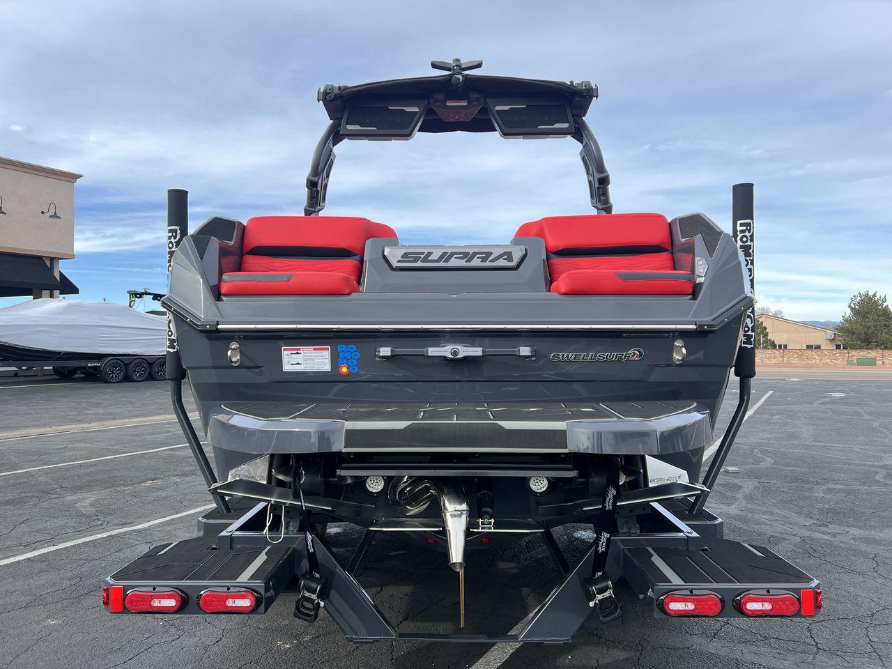 Slide: The Image of 2025 Supra SA boat with red seating, rear view, parked outdoors. - 4