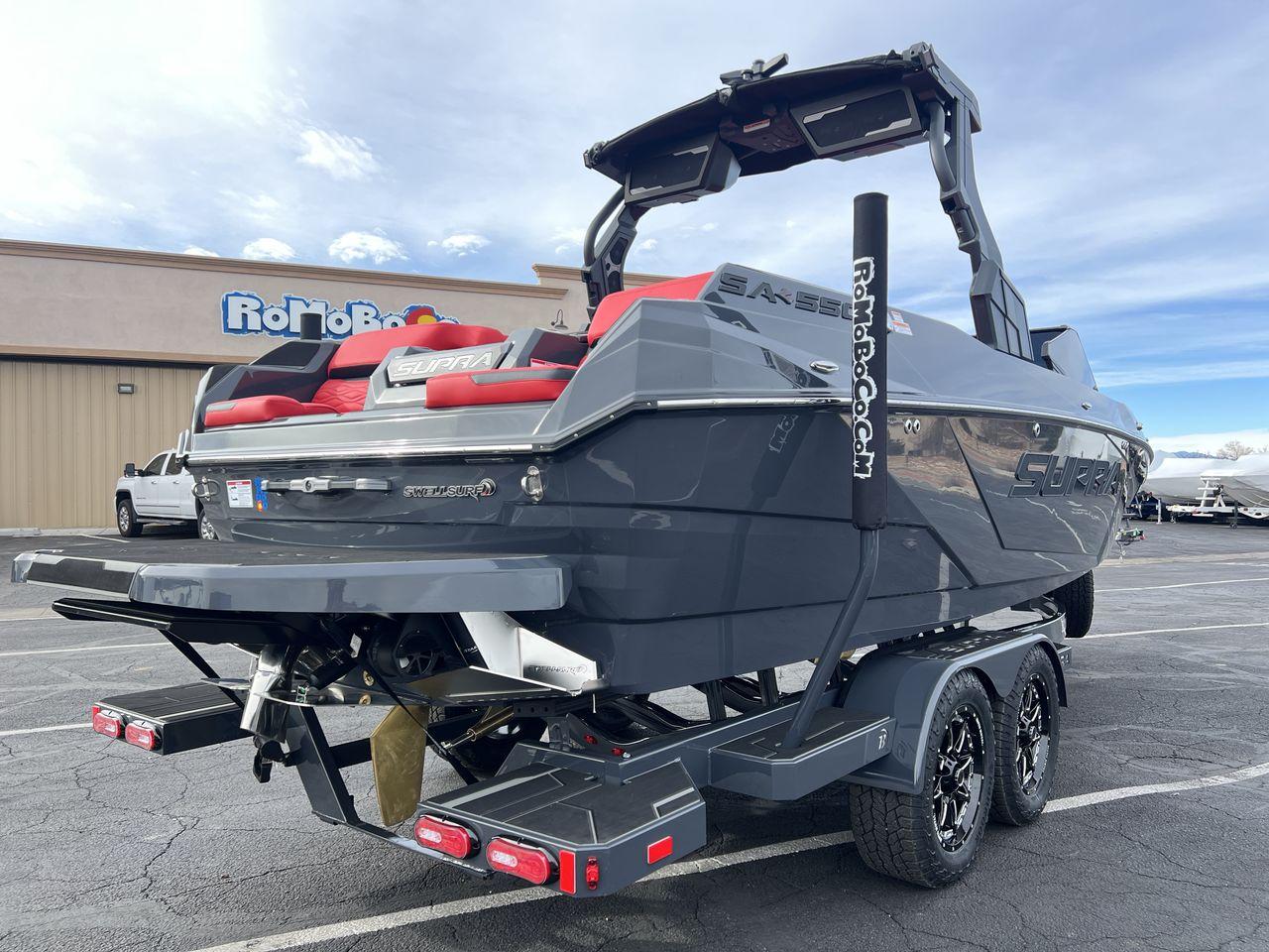 Slide: The Image of 2025 Supra SA boat on trailer, gray with red seats, parked outdoors. - 5