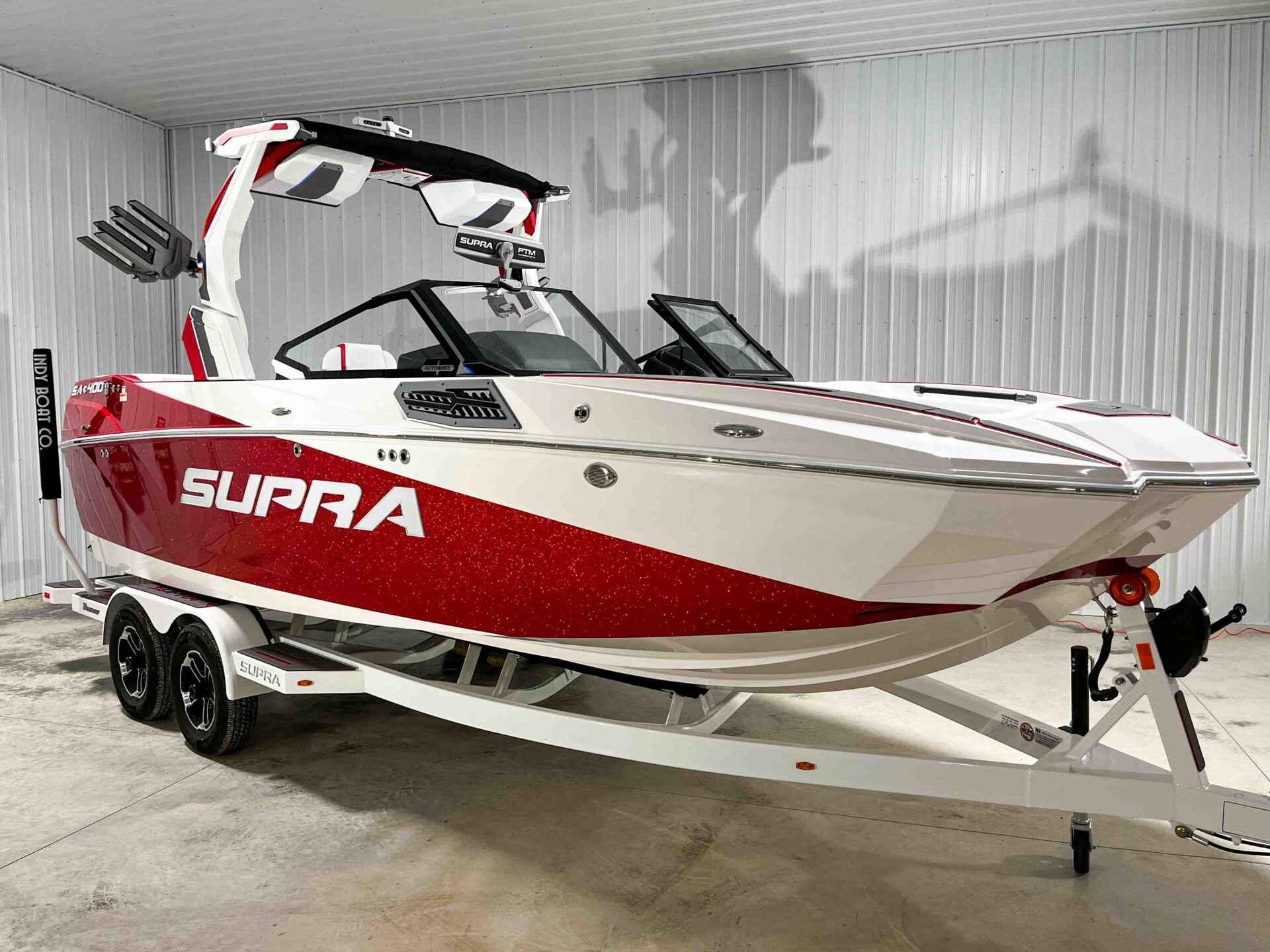 Slide: The Image of 2024 Supra SA400 boat in red and white on a trailer in a garage. - 2