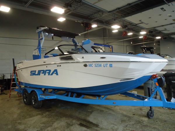 Slide: The Image of 2022 Supra SA 450 boat on a blue trailer in an indoor facility. - 0