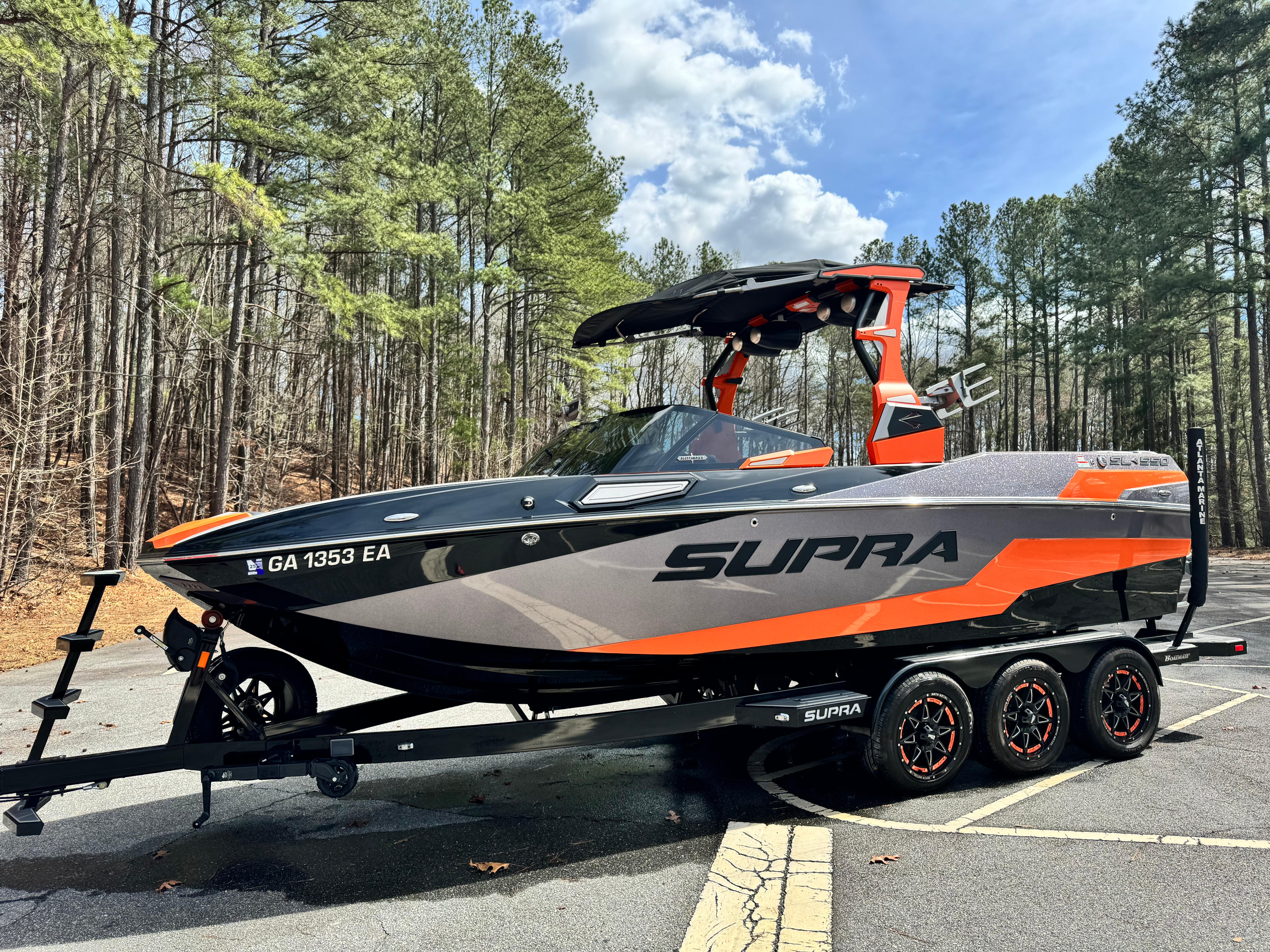 Slide: The Image of 2022 Supra SL 550 boat on trailer in wooded parking area. - 12