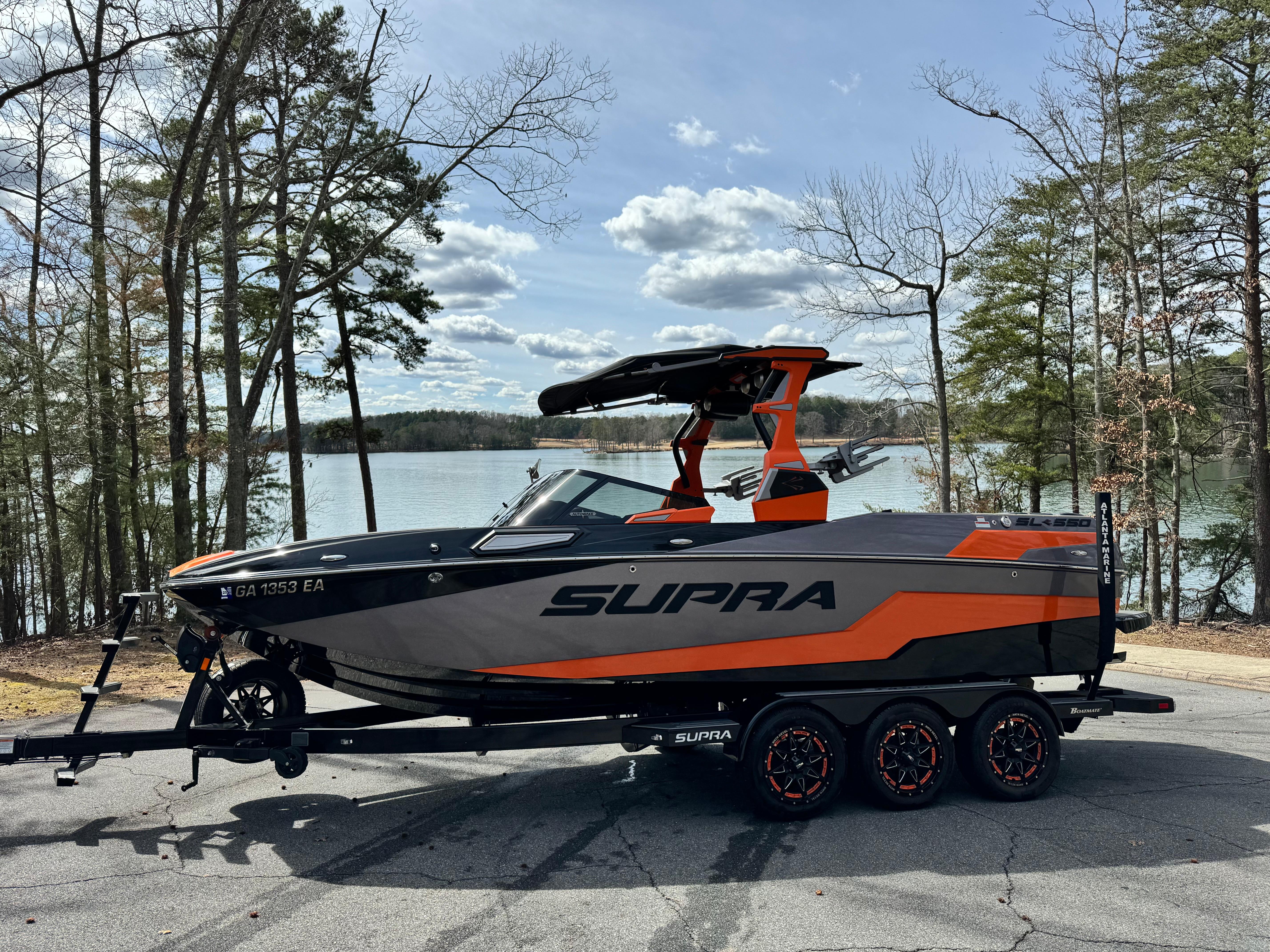 Slide: The Image of 2022 Supra SL 550 boat on trailer by lake, surrounded by trees. - 13