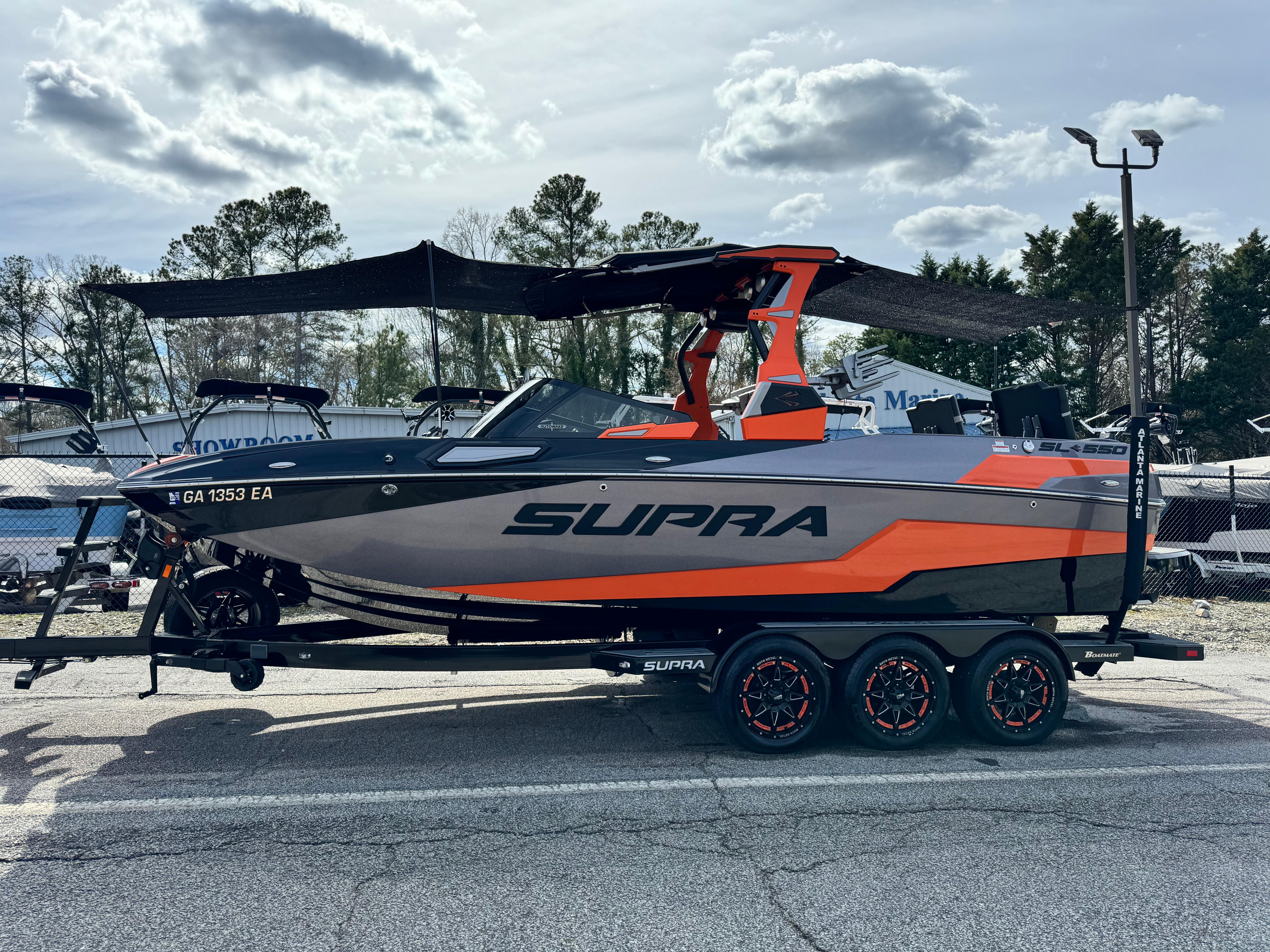 Slide: The Image of 2022 Supra SL 550 boat with orange and gray design on a trailer, parked outdoors. - 14