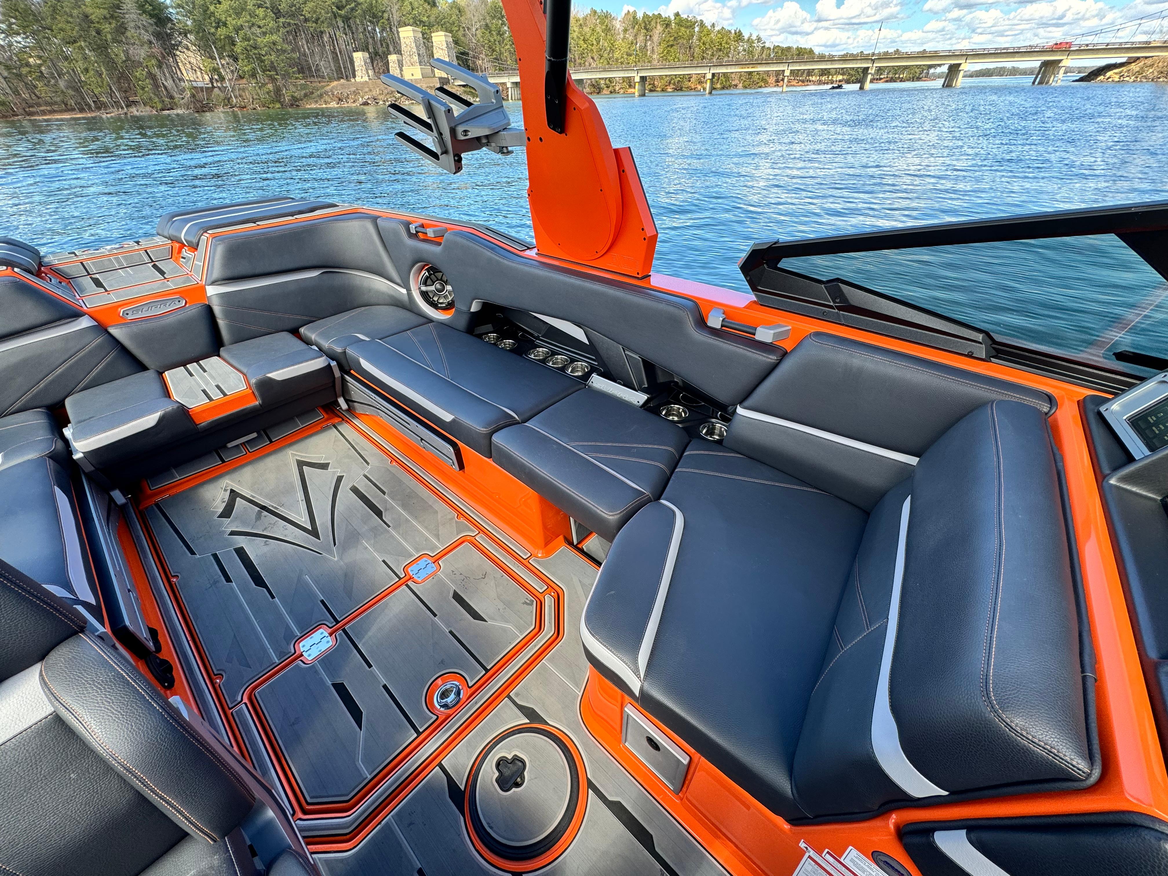 Slide: The Image of 2022 Supra SL 550 boat interior with sleek seating and vibrant orange accents on a lake. - 19