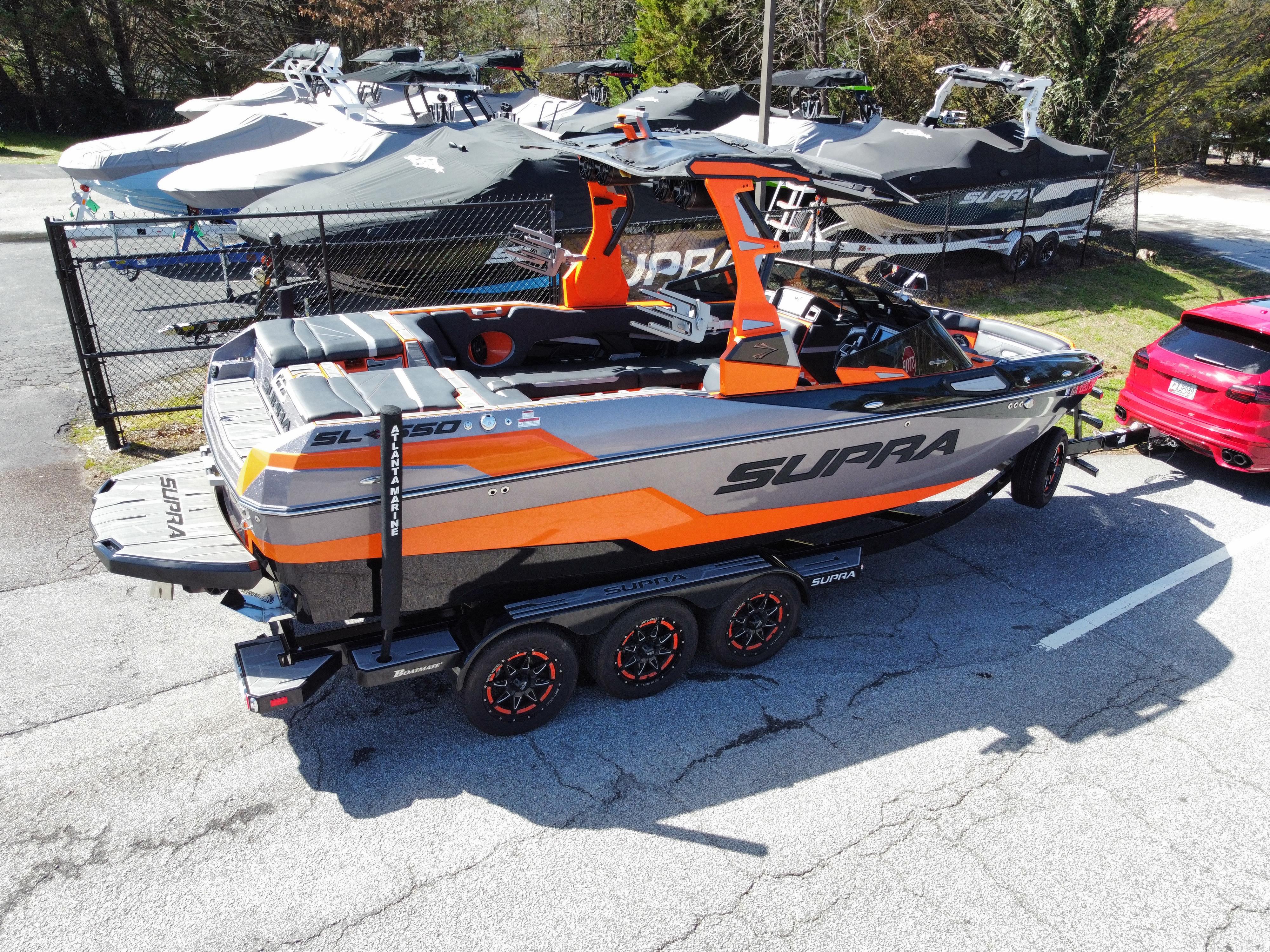 Slide: The Image of 2022 Supra SL 550 boat on trailer, orange and gray design, parked outdoors. - 20