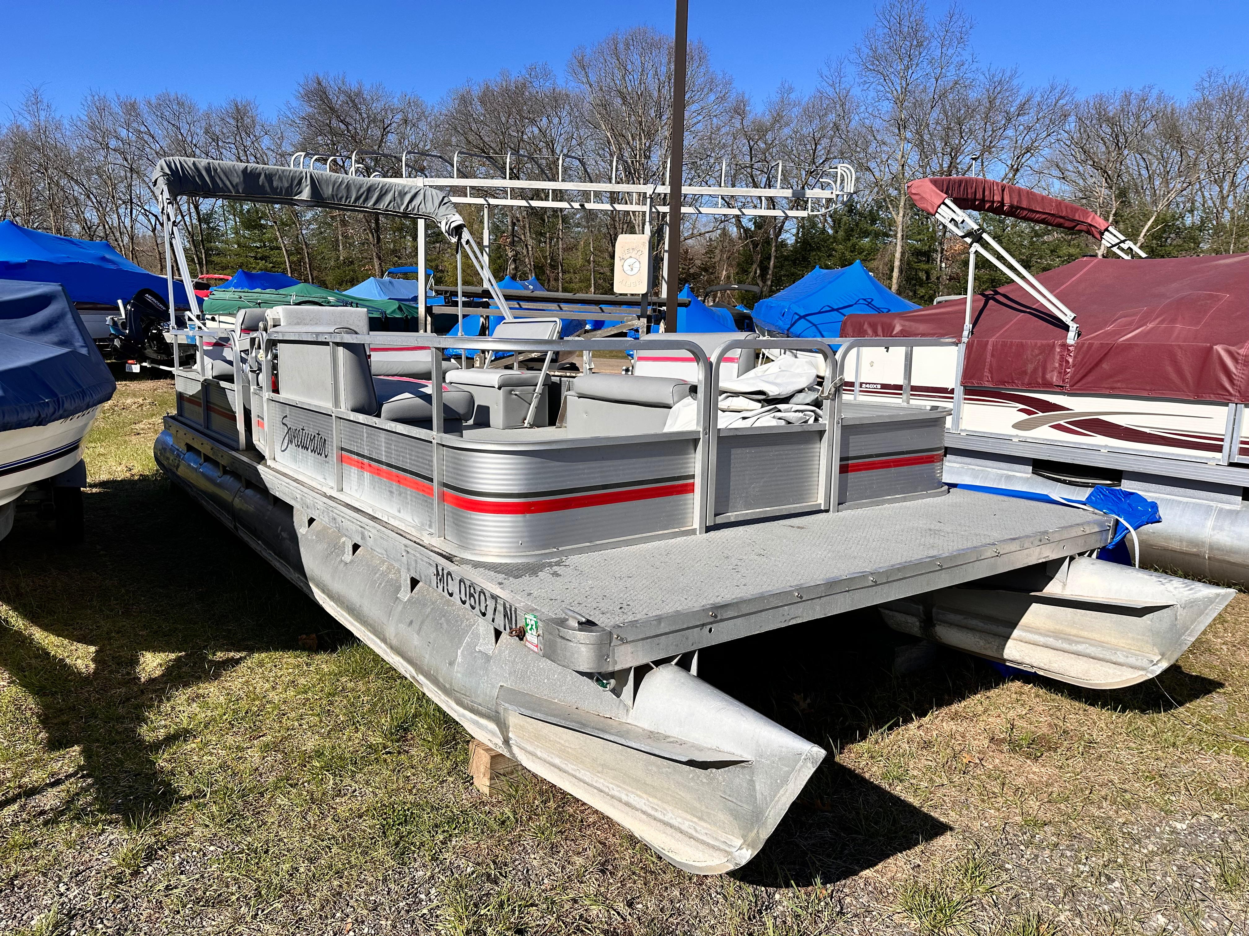 Slide: The Image of 1987 Sweetwater Pontoon boat in storage lot with other boats. - 1