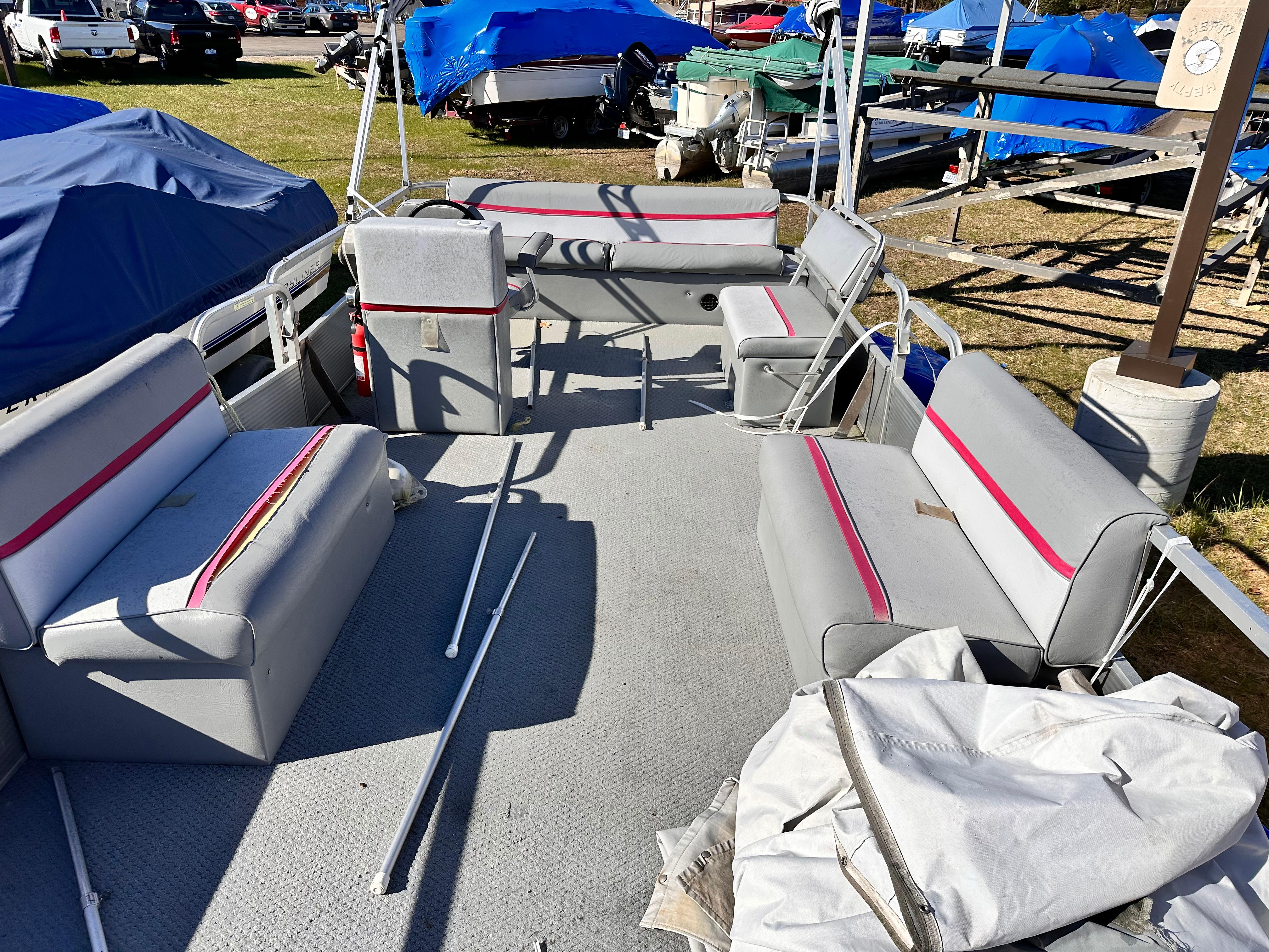 Slide: The Image of 1987 Sweetwater Pontoon boat interior with gray and pink seating, parked outdoors. - 4