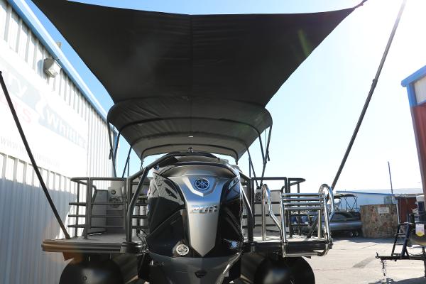 Slide: The Image of 2025 Sylvan L3 DLZ Bar Tri-Toon boat with canopy, docked outdoors. - 2