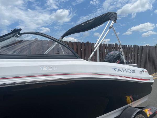 Slide: The Image of 2024 Tahoe 185 S boat with black and white exterior, docked under a blue sky. - 1