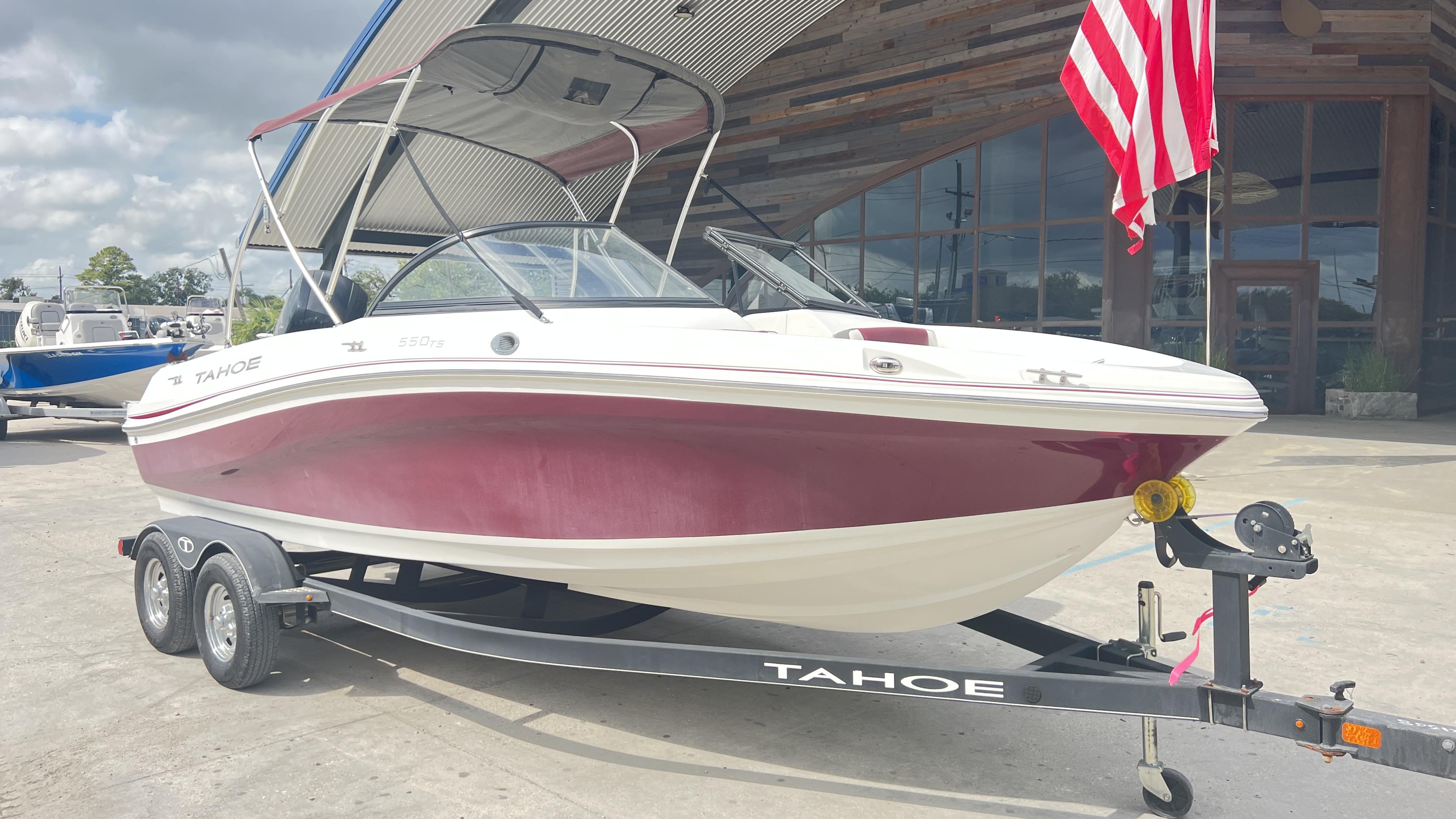 Slide: The Image of 2018 Tahoe 550 TS boat on trailer, red and white, parked outdoors. - 1