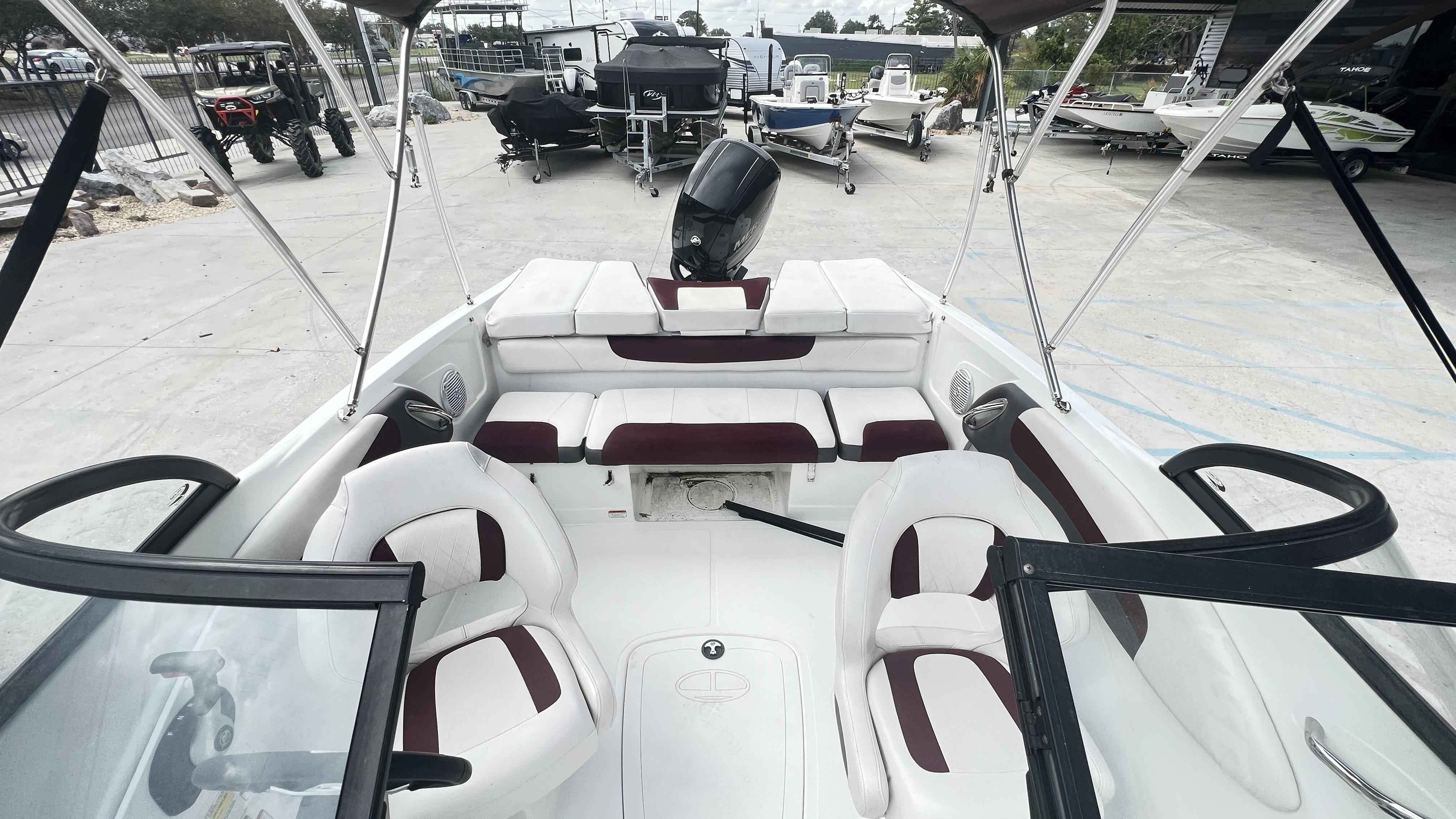 Slide: The Image of 2018 Tahoe 550 TS boat interior with white and maroon seating, parked in a marina. - 10