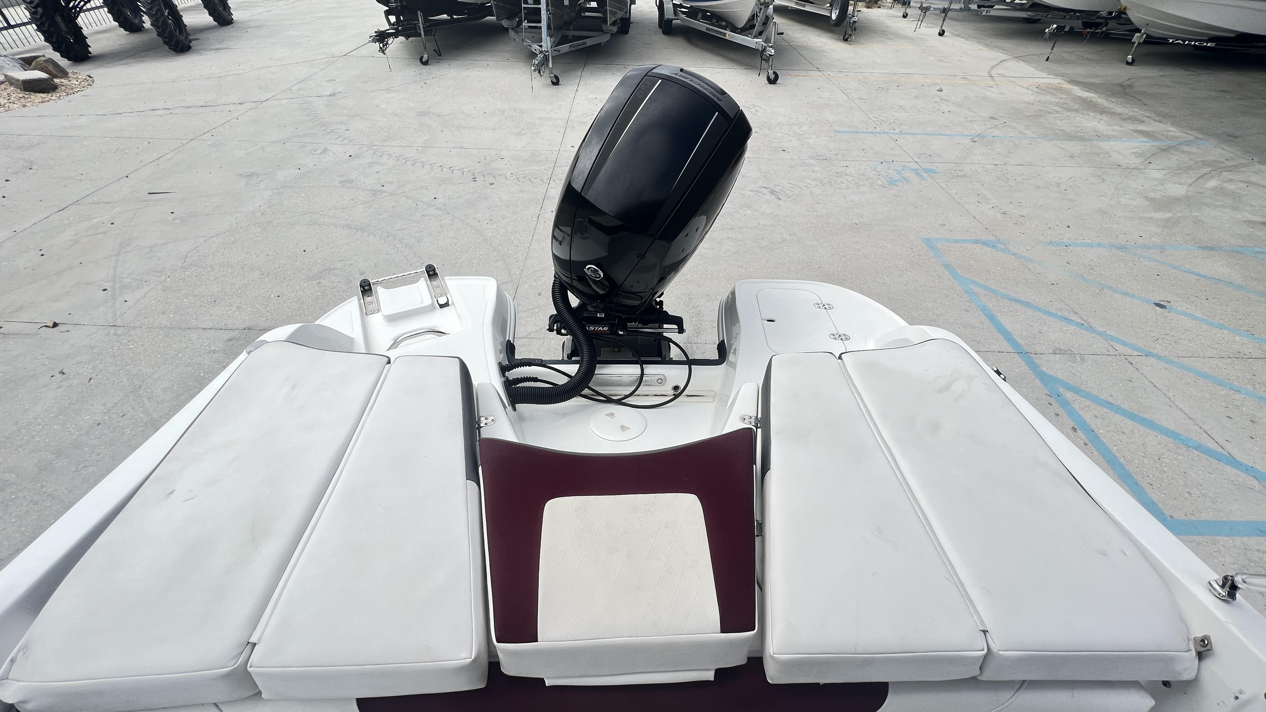 Slide: The Image of 2018 Tahoe 550 TS boat with outboard motor and cushioned seating, parked on concrete. - 11