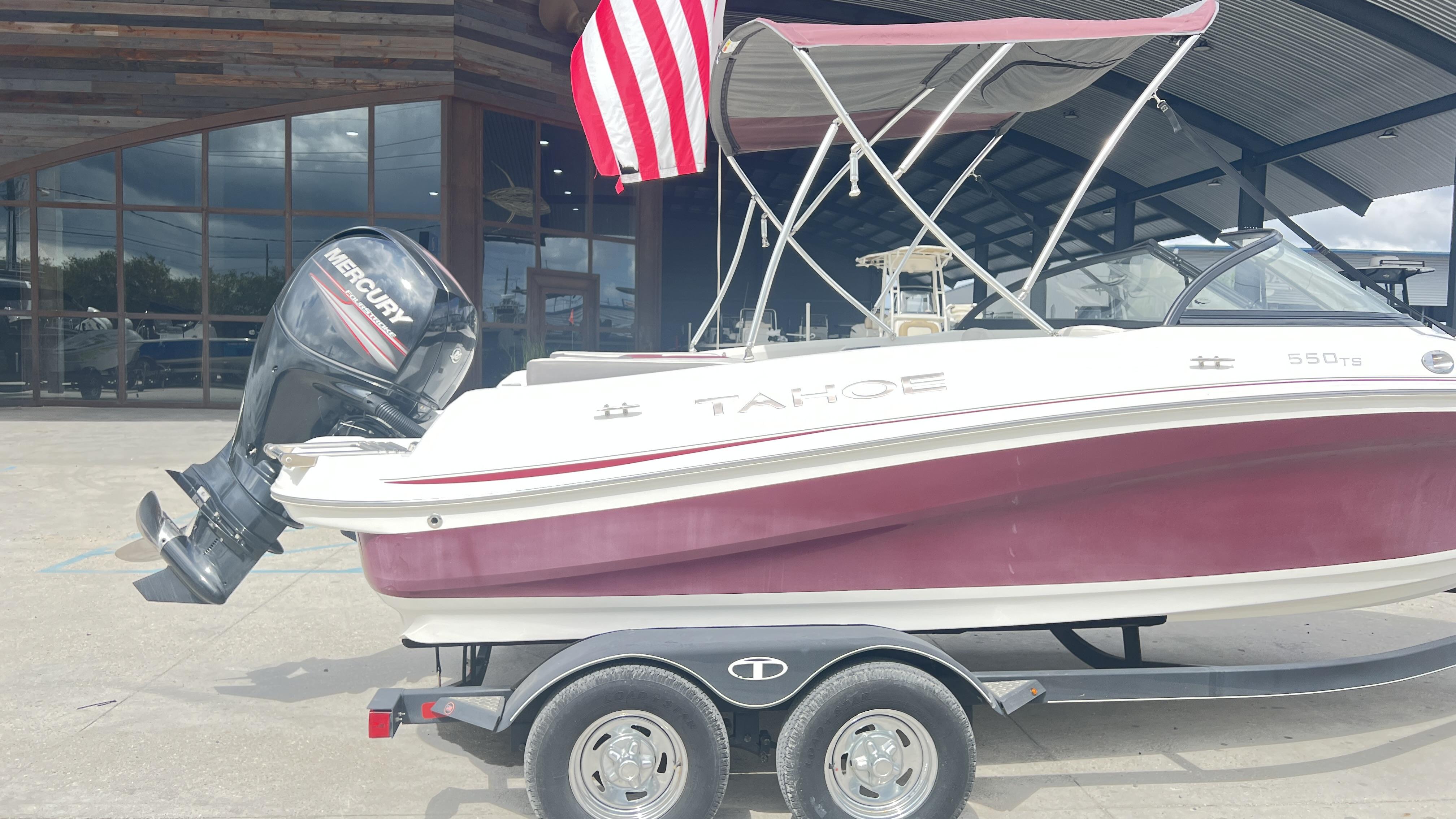 Slide: The Image of 2018 Tahoe 550 TS boat with Mercury engine on trailer, parked outside a building. - 2