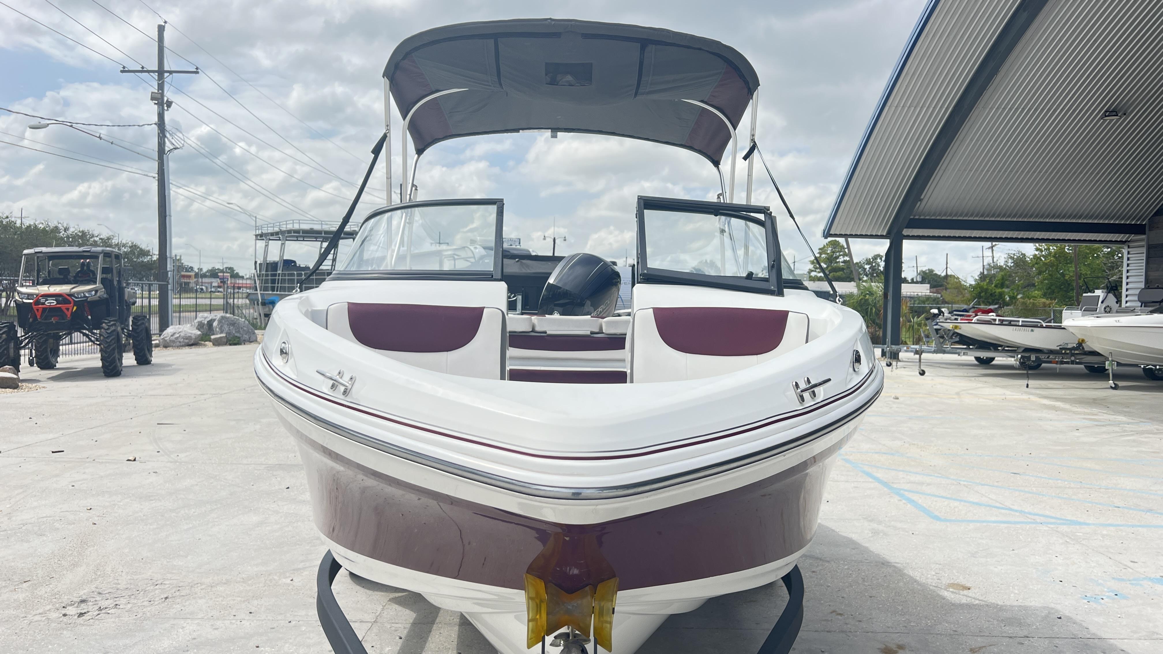 Slide: The Image of 2018 Tahoe 550 TS boat with maroon accents, parked outdoors under a cloudy sky. - 3