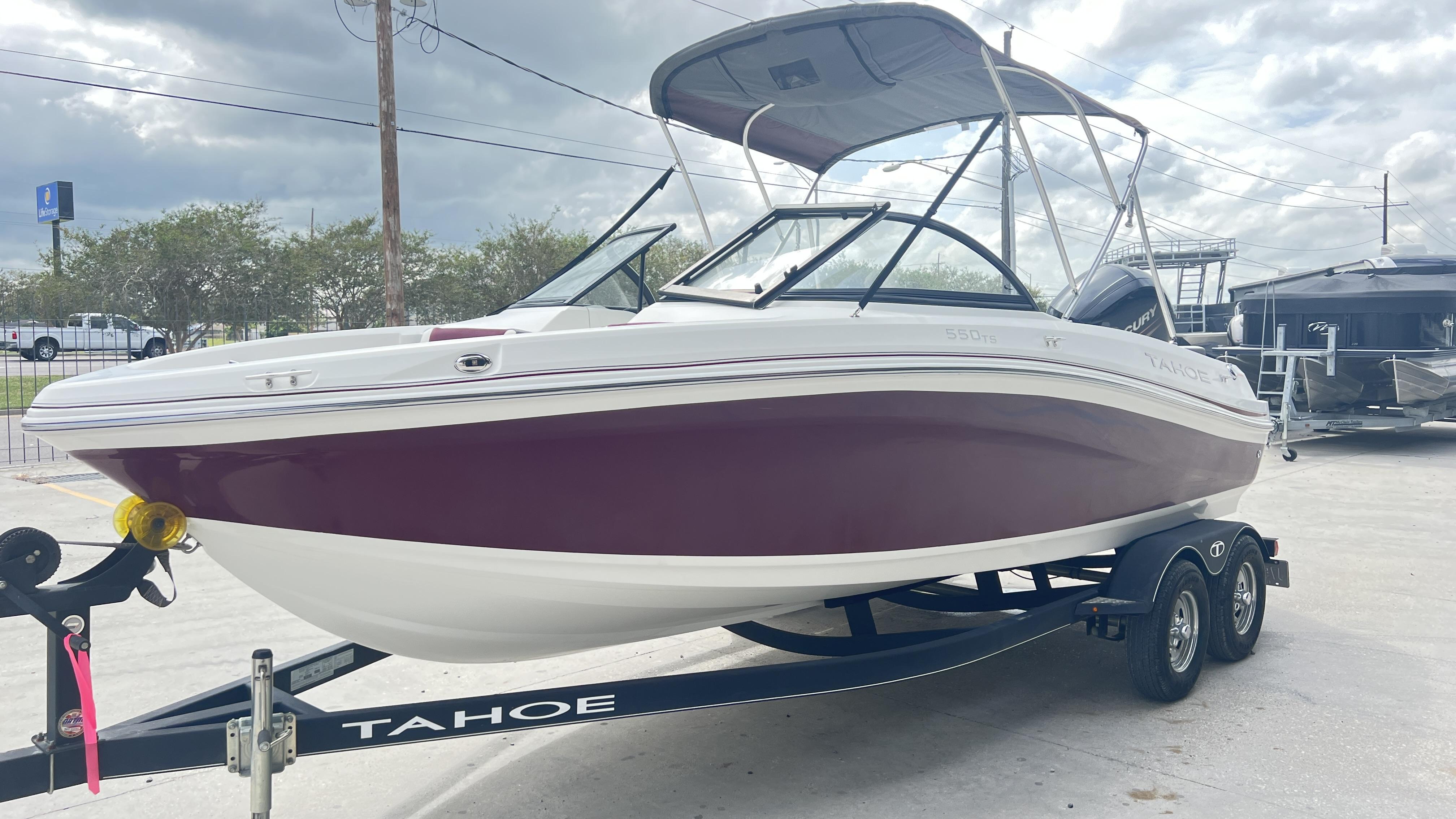 Slide: The Image of 2018 Tahoe 550 TS boat on trailer, featuring maroon and white design, parked outdoors. - 5