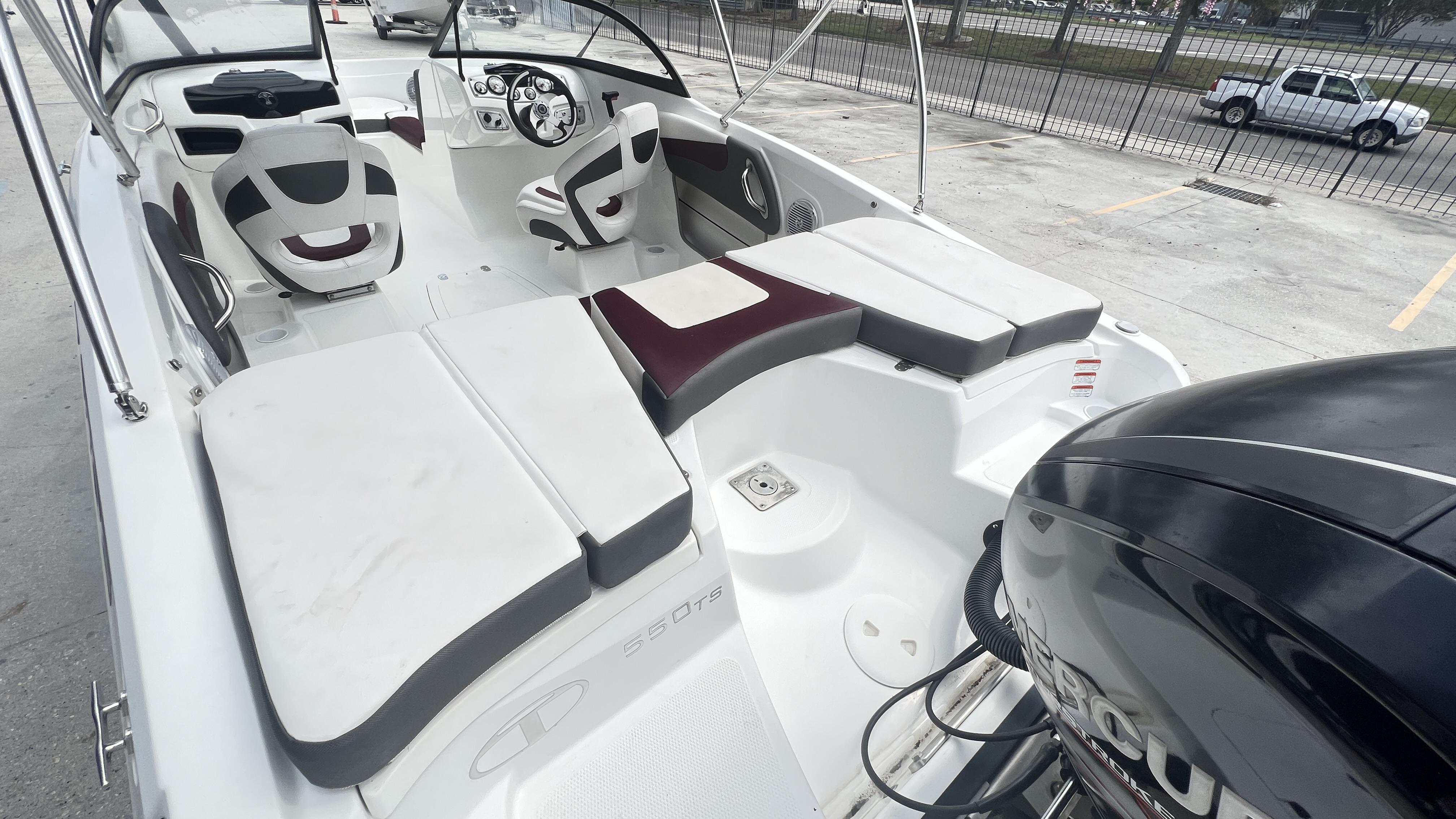 Slide: The Image of 2018 Tahoe 550 TS boat interior with seating and steering wheel, parked outdoors. - 8