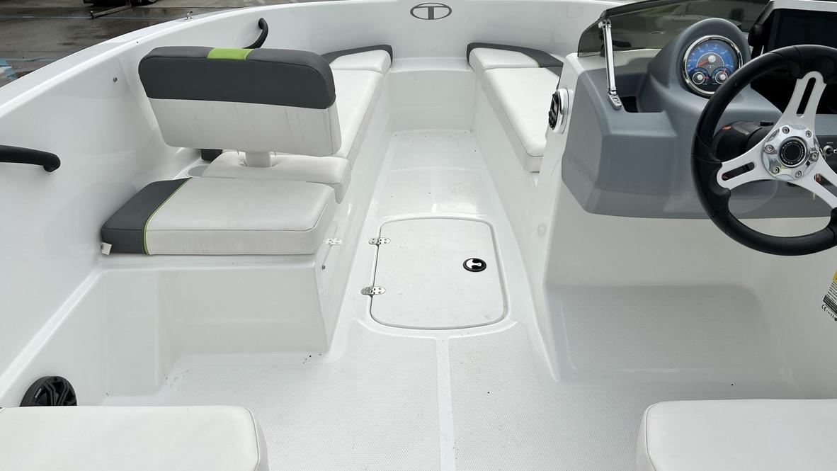 Slide: The Image of 2021 Tahoe T16 boat interior with white and gray seating, steering wheel, and storage compartment. - 17