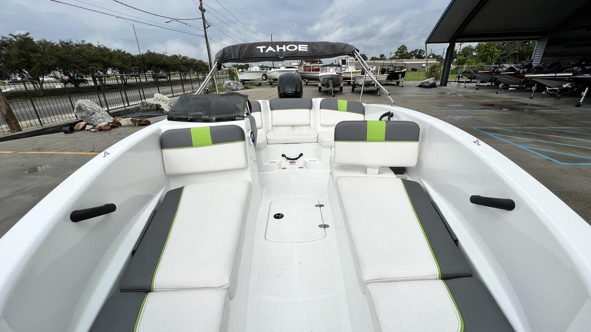 Slide: The Image of 2021 Tahoe T16 boat with white and green seating, docked outdoors. - 2
