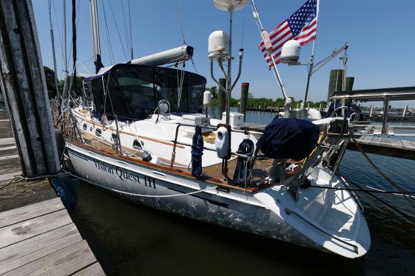 Slide: The Image of 1988 Tayana 52 sailboat docked at a marina with an American flag. - 1