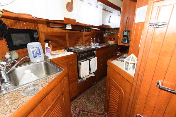 Slide: The Image of 1988 Tayana 52 yacht kitchen with wooden cabinetry, granite countertops, and modern appliances. - 26