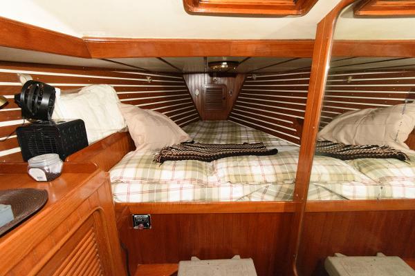 Slide: The Image of Cozy cabin interior of 1988 Tayana 52 sailboat with wooden paneling and plaid bedding. - 31