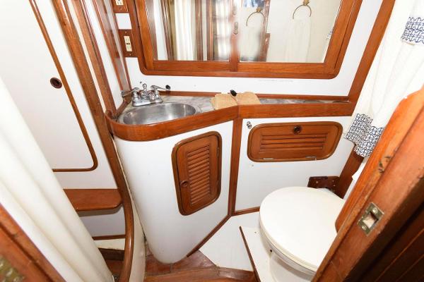 Slide: The Image of 1988 Tayana 52 yacht bathroom with sink, toilet, wooden cabinets, and mirror. - 32