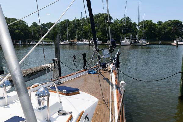 Slide: The Image of 1988 Tayana 52 sailboat docked in a serene marina with other boats. - 8