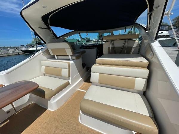 Slide: The Image of 2012 Tiara Yachts 3100 Coronet interior with beige seating and wooden table, docked at marina. - 16