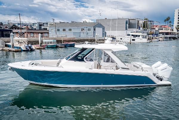 Slide: The Image of 2024 Tiara Yachts 34LS boat in a marina with blue hull and white deck. - 2