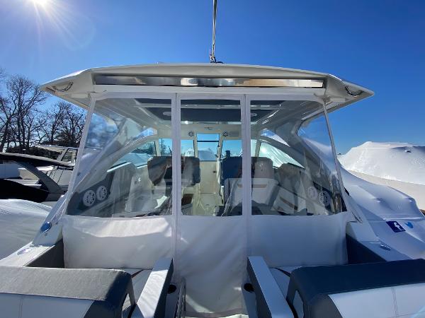 Slide: The Image of 2021 Tiara Yachts 34 LX boat with clear enclosure under bright blue sky. - 16