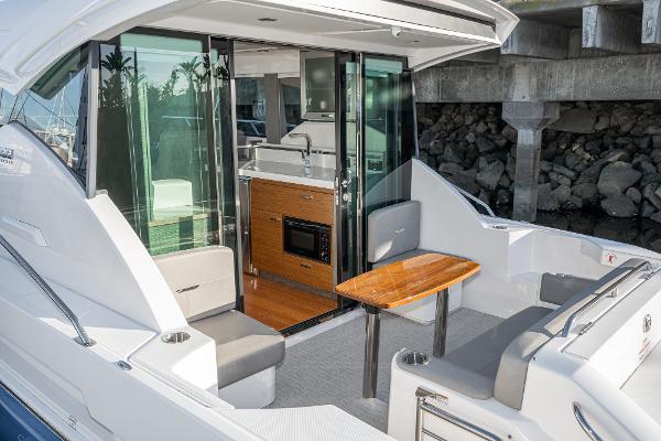 Slide: The Image of 2020 Tiara Yachts 39 Coupe with outdoor seating and kitchenette, docked by a stone wall. - 7