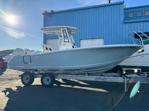 Slide: The Image of 2024 Tidewater 256 LXF boat on a trailer in front of a blue building. - 0