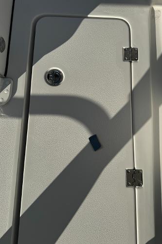 Slide: The Image of 2024 Tidewater 256 LXF boat storage compartment door with latch and hinges. - 6