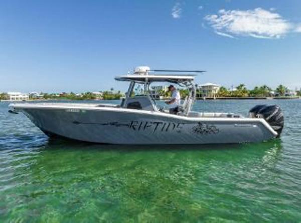 Slide: The Image of 2020 Tidewater 320 CC Adventure boat on clear water, sunny day, side view. - 4