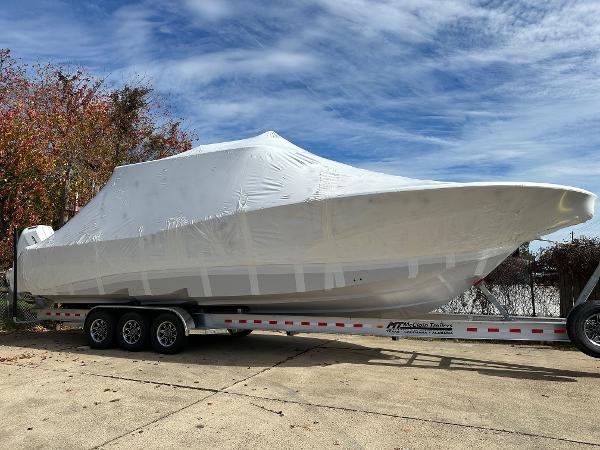 Slide: The Image of 2024 Tidewater 380 CC Adventure boat covered on a trailer, outdoors. - 0