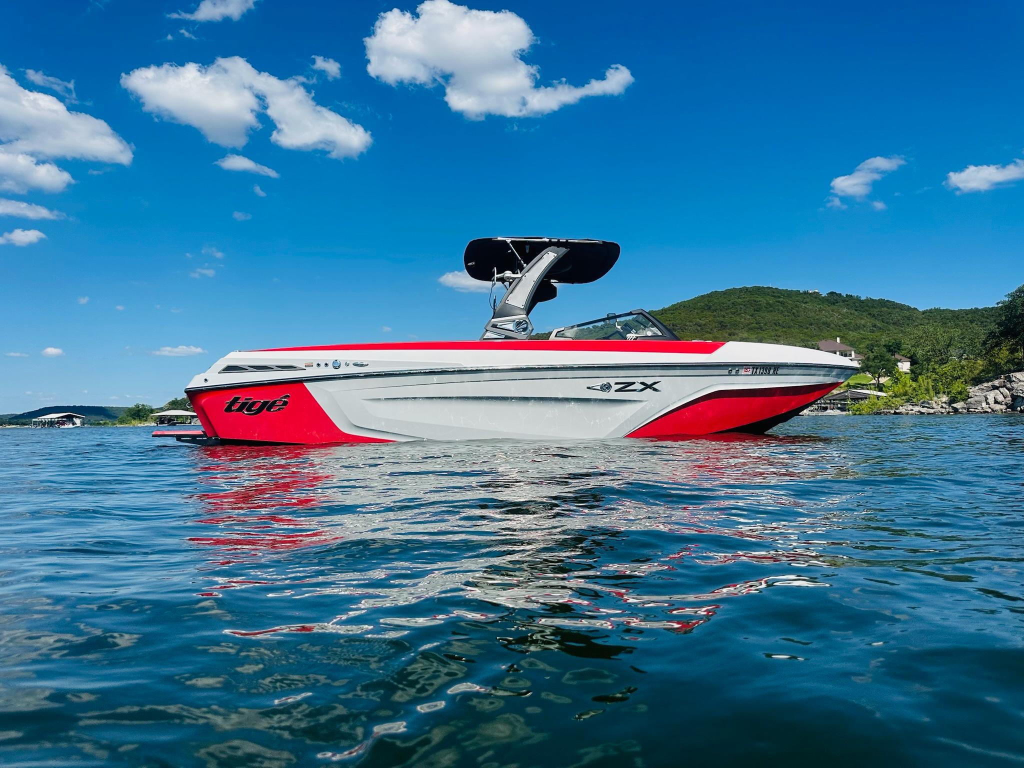 Slide: The Image of 2020 Tigé 25ZX boat on a lake under a clear blue sky. - 0